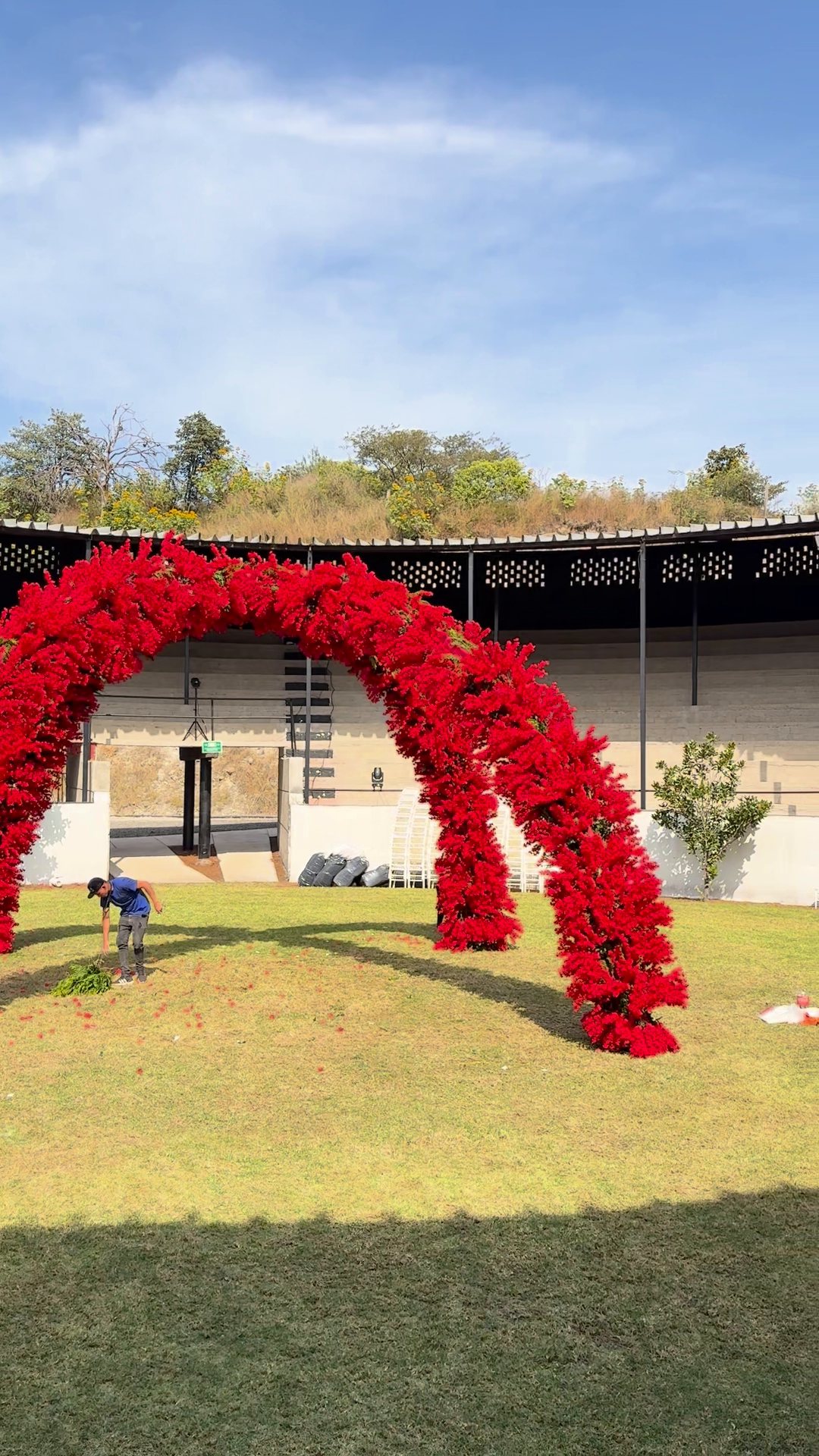 Doble arco de flor roja terminado en el centro de un ruedo al aire libre