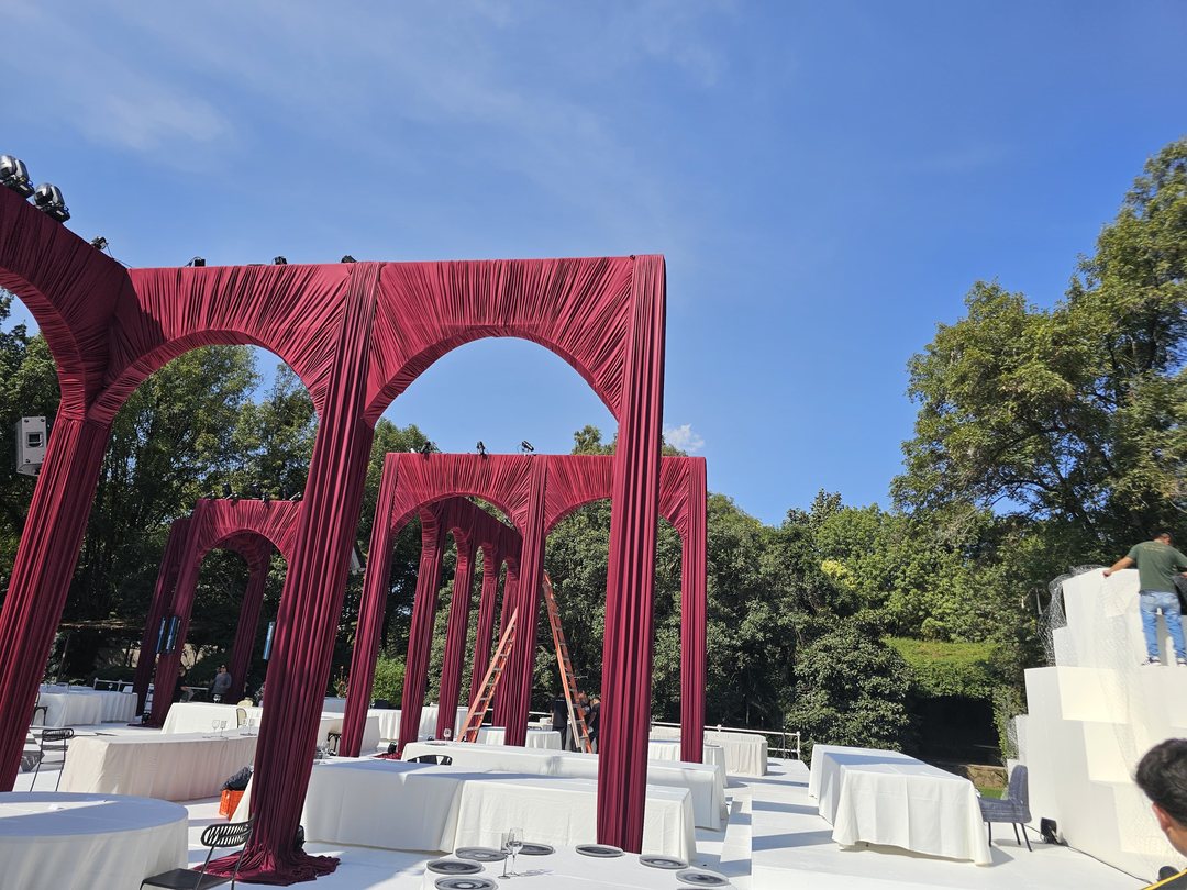 Arcos forrados de tela roja en un jardín, durante el montaje