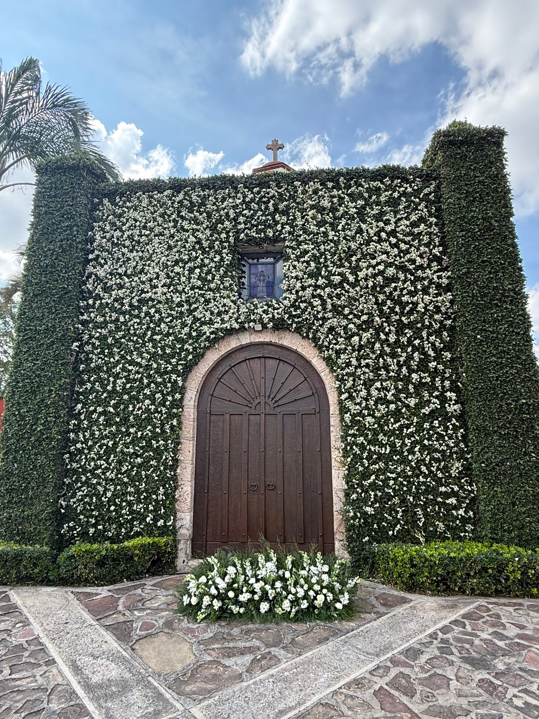 Capilla de piedra forrada con un muro floral de follaje y flor blanca para la ceremonia, Zapopan