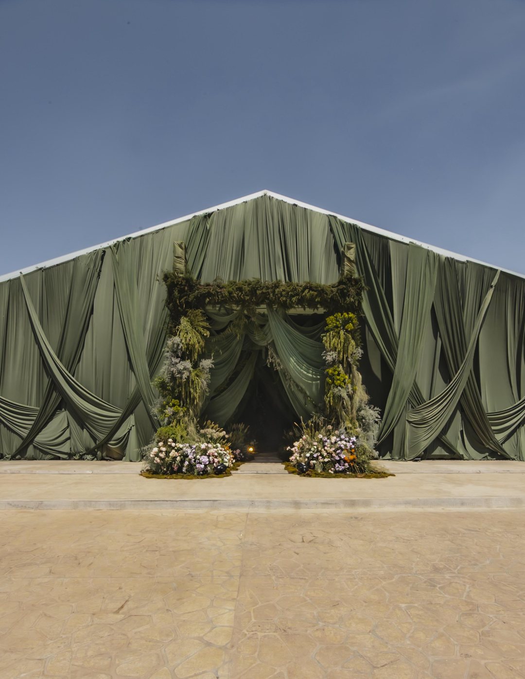 Carpa forrada de tela verde con una entrada de follaje y flor