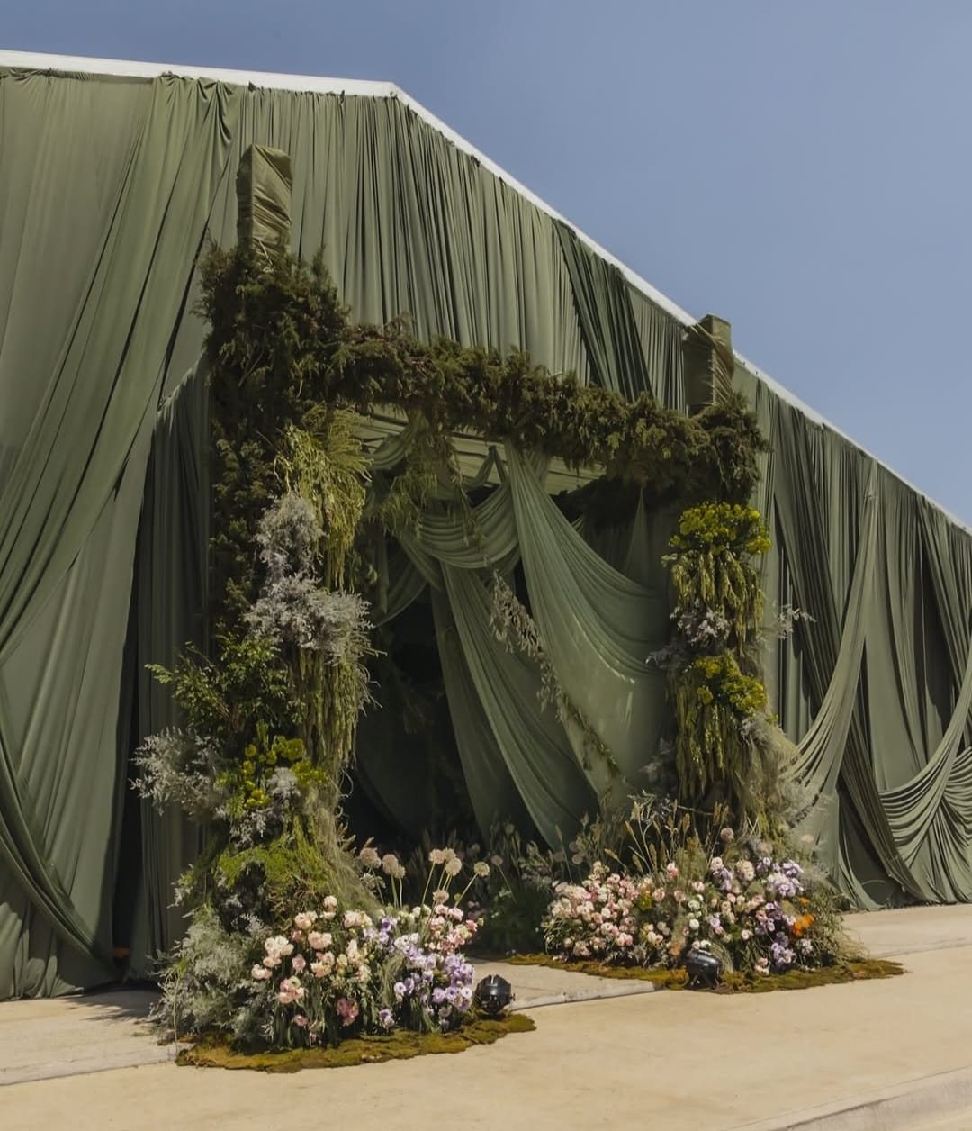 Entrada de follaje y flor sobre la carpa forrada de tela verde