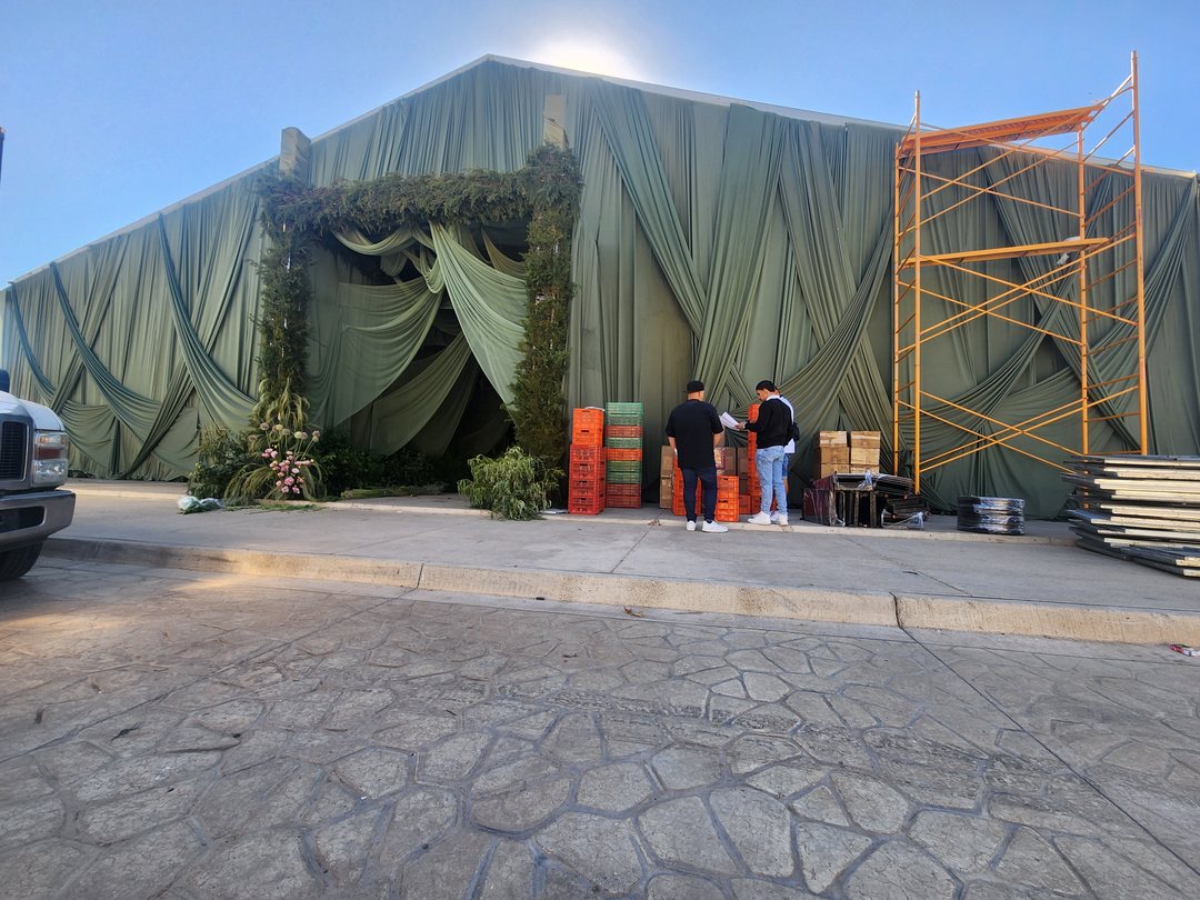 Carpa forrada de tela verde durante el montaje, con andamio en la entrada