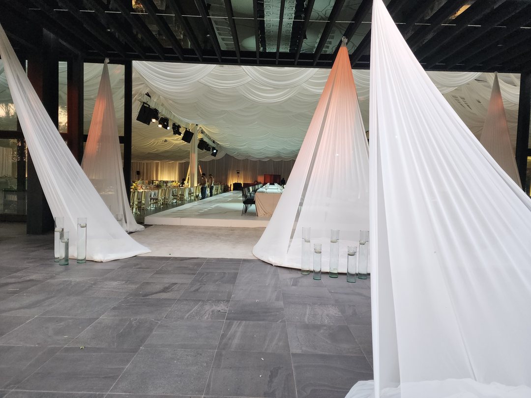 Conos de tela blanca y techo en drapeado en un salón abierto, antes de montar las mesas