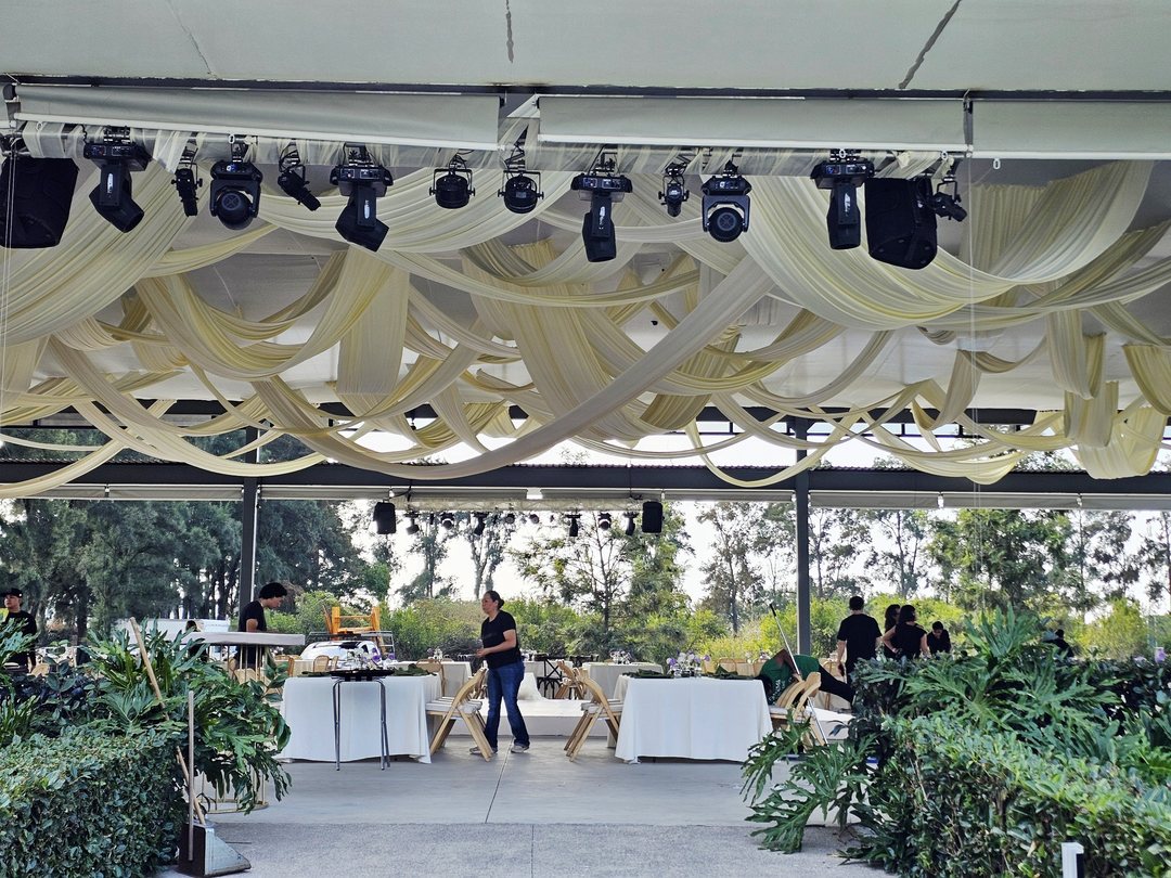 Techo de tela crema en drapeado sobre una terraza abierta junto al jardín