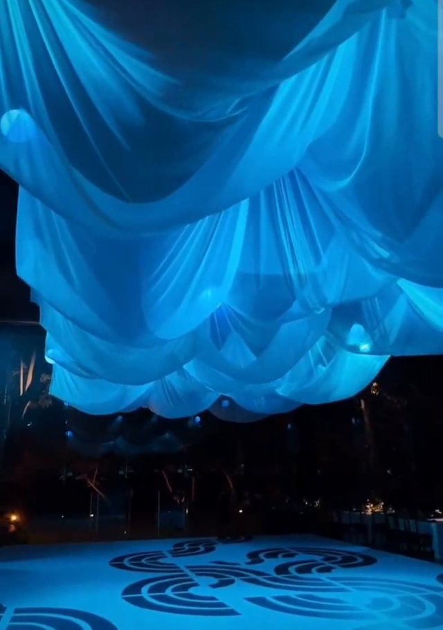 Entelado cinético azul visto desde abajo: la tela forma ondas alrededor de las esferas de luz