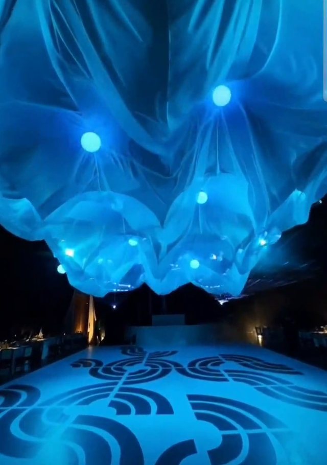 Entelado cinético azul sobre la pista: las esferas de luz levantan la tela y la pista se ilumina de azul