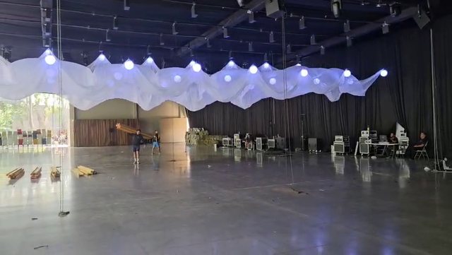 Entelado cinético blanco en un salón de día: las esferas de luz levantan la tela en ondas