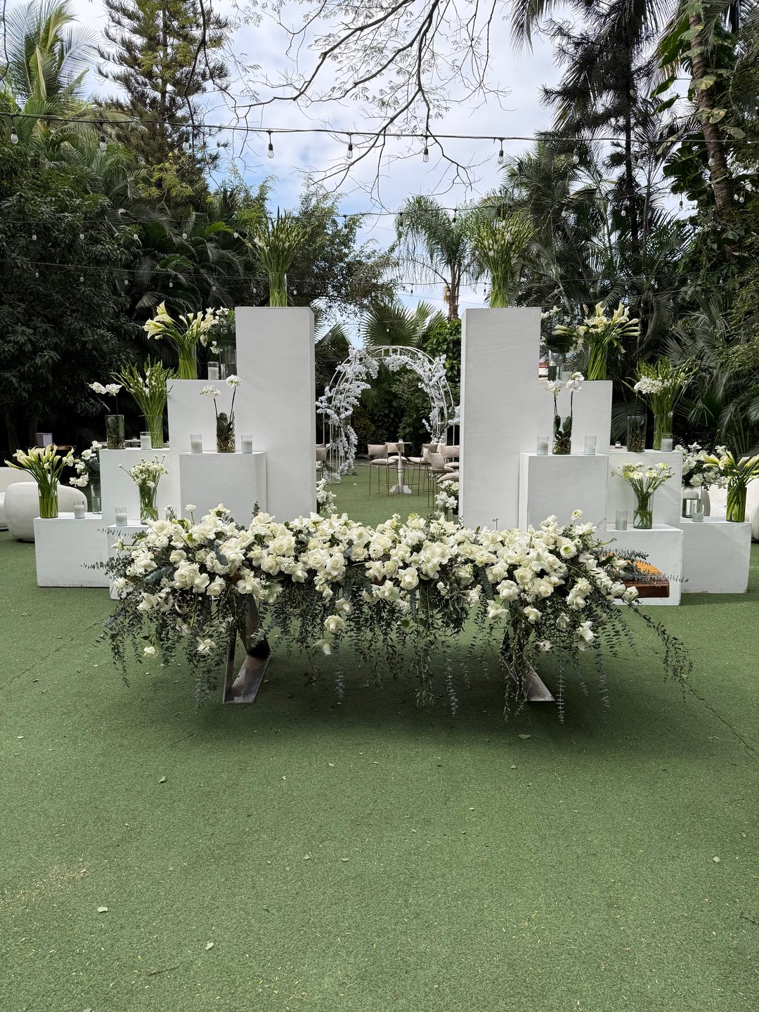 Mesa de honor con arreglo largo de flor blanca sobre bloques blancos, jardín tropical en Riviera Nayarit
