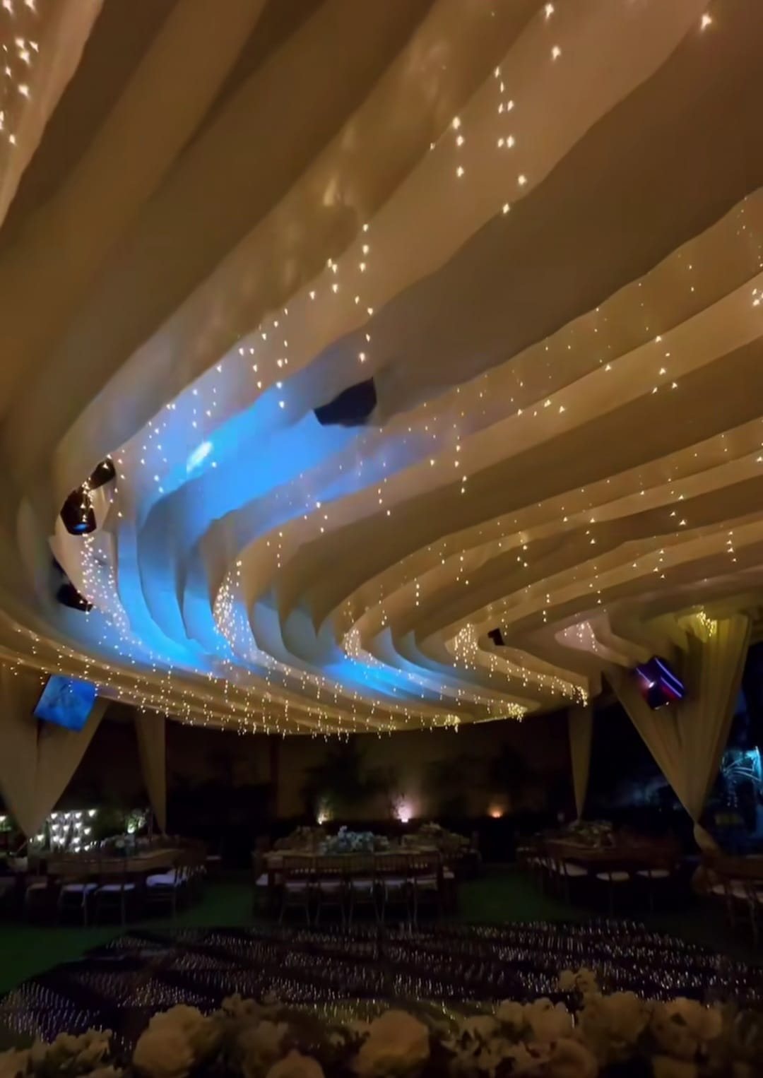 Ondas de tela beige con luces azules y series de luz sobre un salón de noche