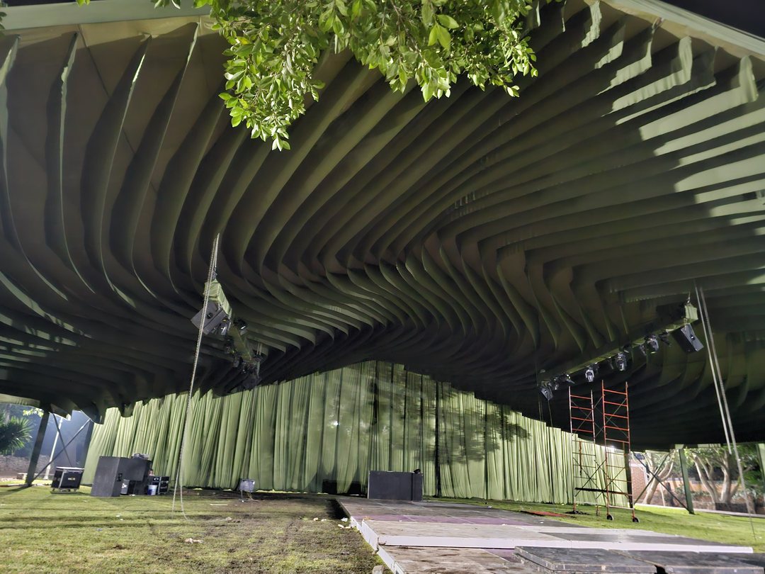 Ondas de tela verde sobre un jardín, durante el montaje