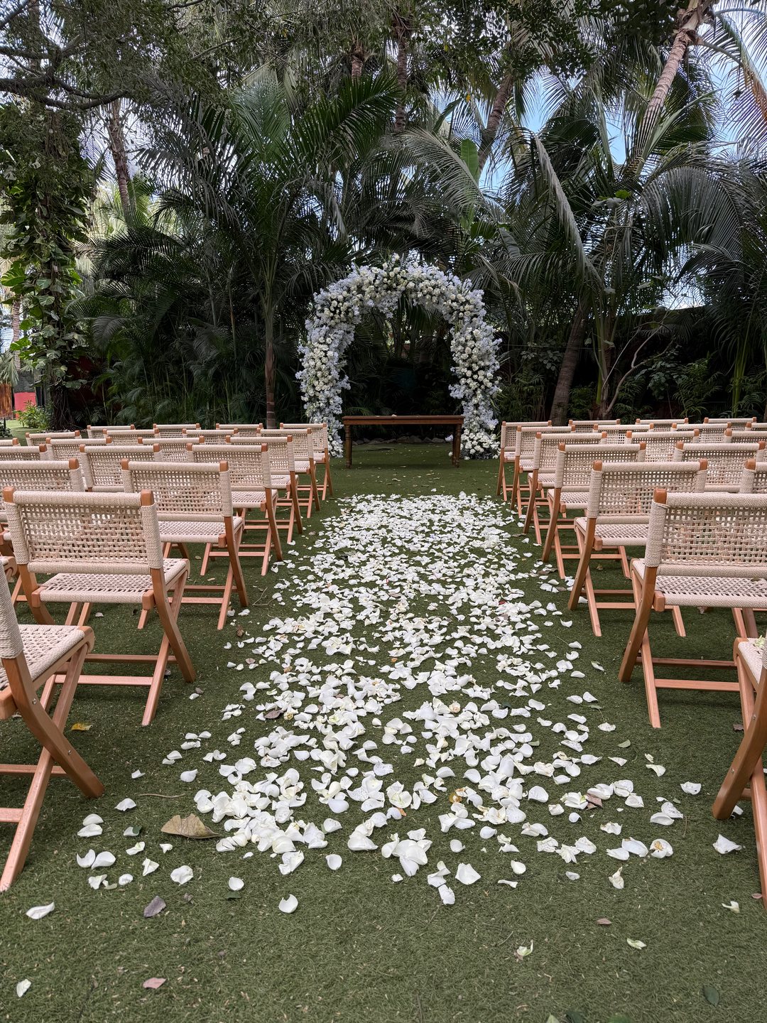 Pasillo de pétalos blancos hacia el arco floral de la ceremonia, jardín tropical en Riviera Nayarit