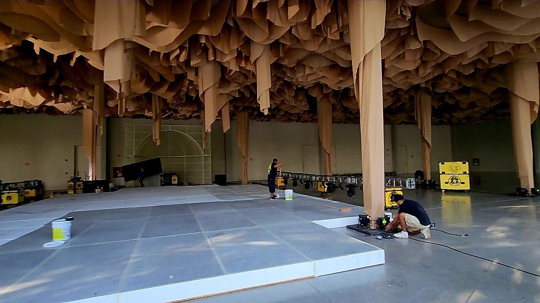 Techo de tiras de tela beige con columnas forradas mientras se arma la pista