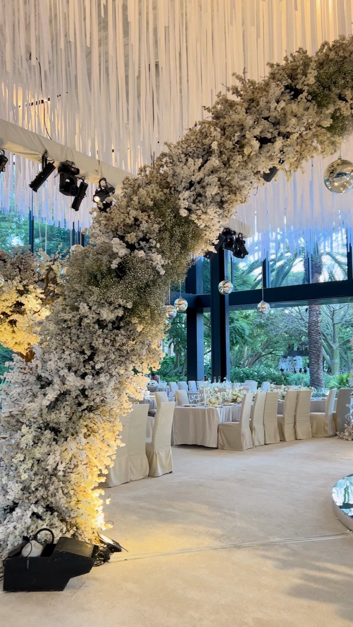 Decoración aérea con telas: cielo de tiras blancas y esferas de espejo sobre un arco floral doble y pista de espejo