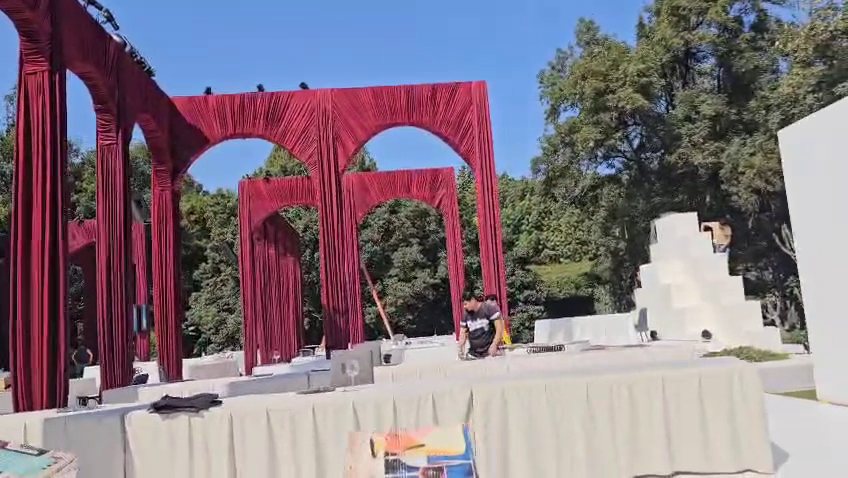 Arcos forrados de tela roja en un jardín, durante el montaje