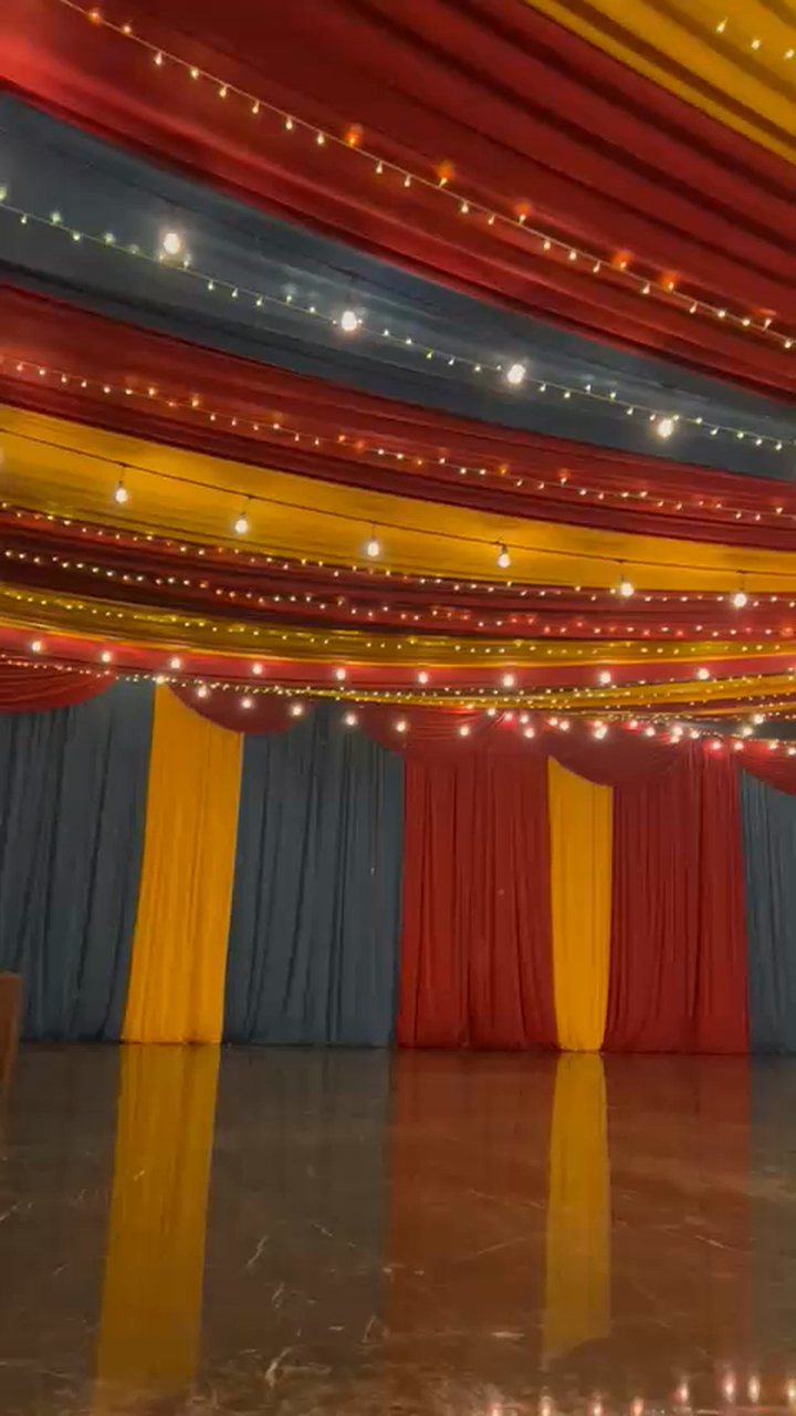 Techo de tela en rojo, amarillo y azul tipo circo con series de luz sobre una pista redonda
