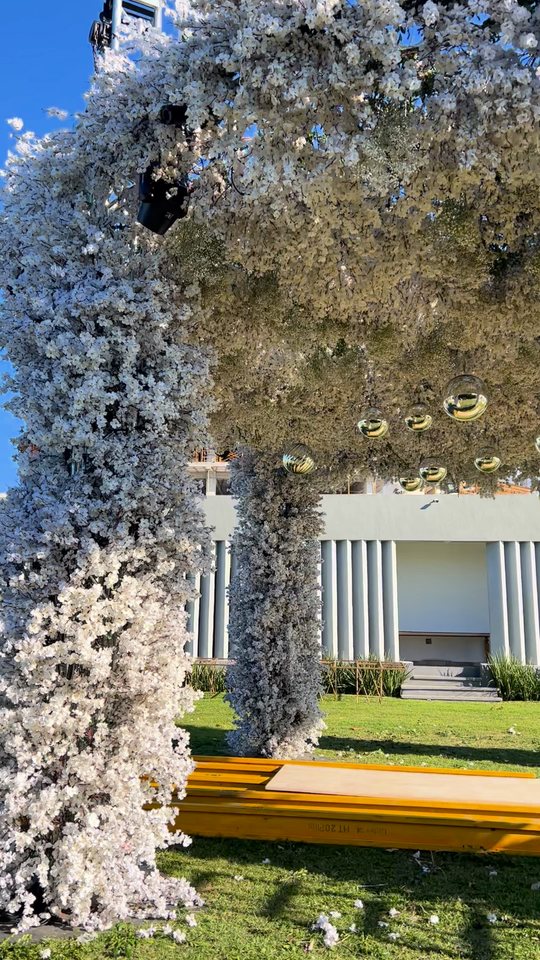 Bajo un domo de flor blanca nevada con esferas de espejo, sobre columnas forradas de flor, en un jardín