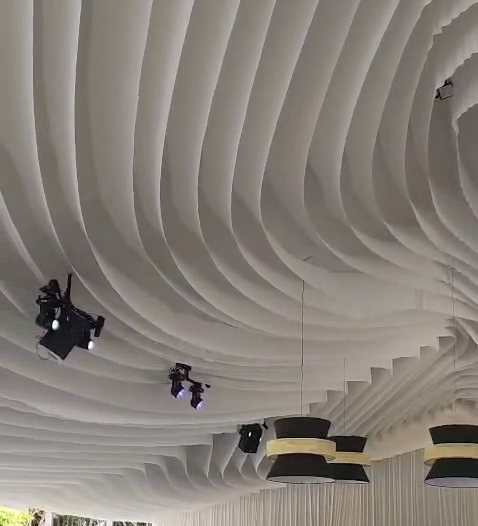 Techo de ondas de tela blanca en espiral con lámparas negras colgantes