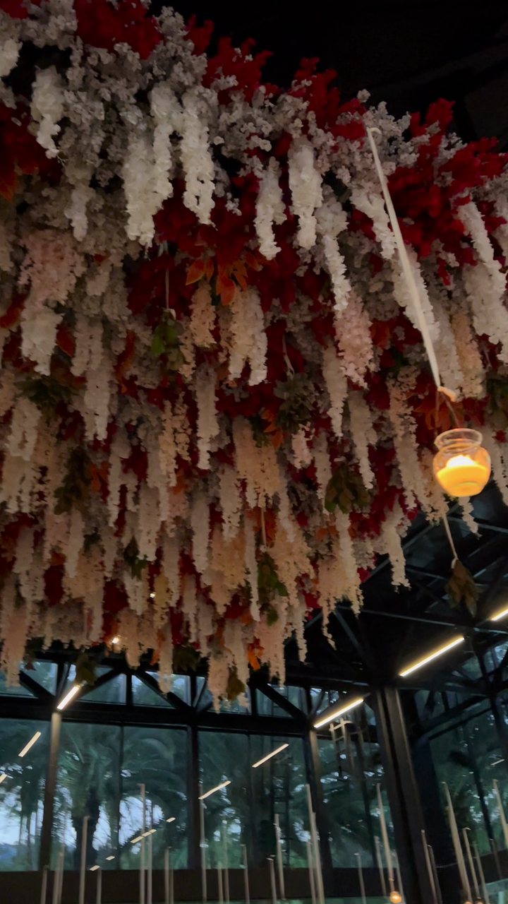 Decoración aérea de flor blanca y roja con veladoras sobre la pista y las mesas, pabellón de cristal de noche